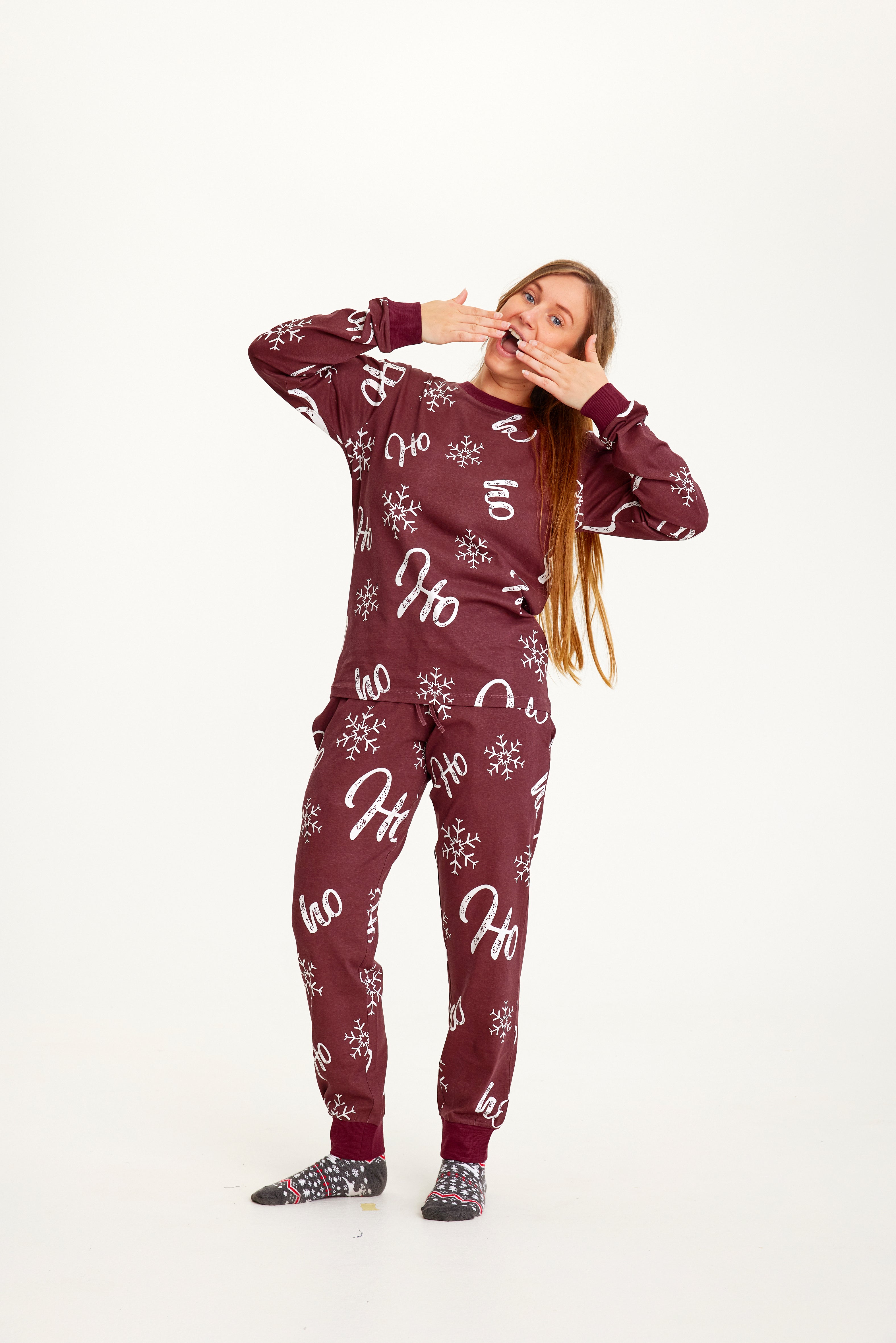 Een gapende vrouw in een donkerrode kerstpyjama.